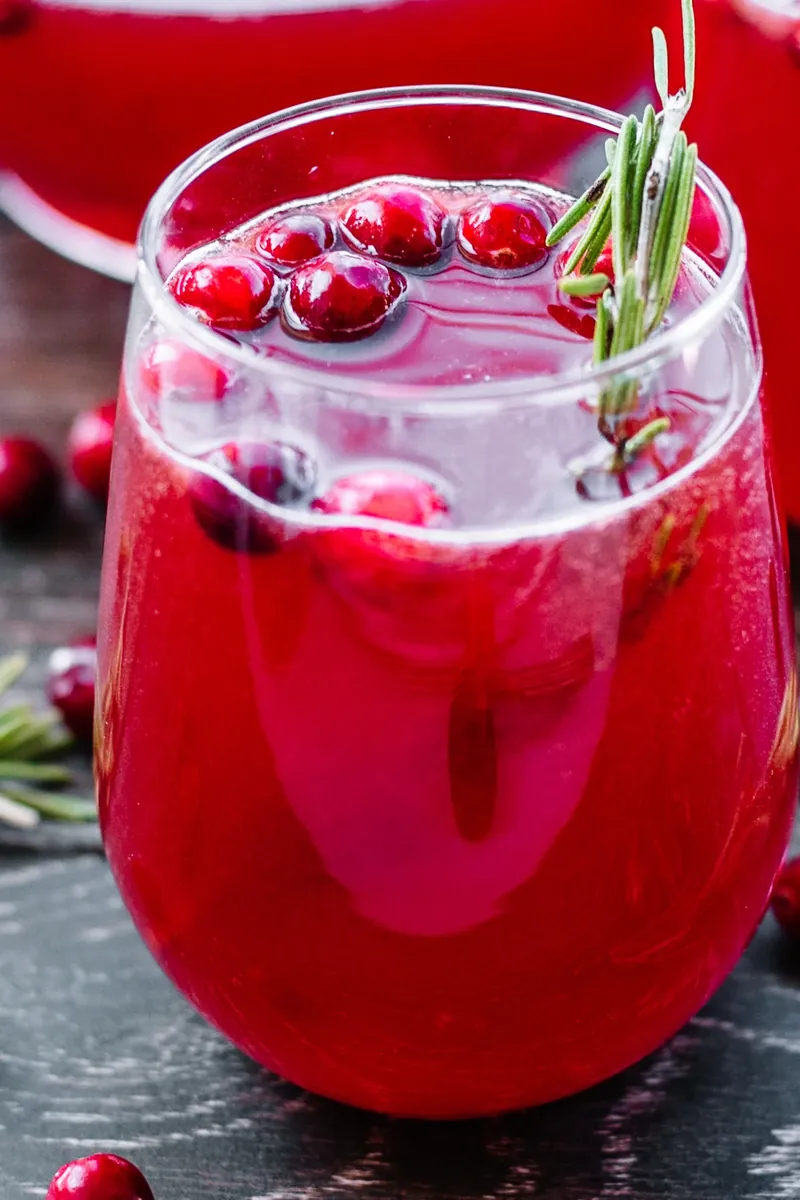 Elegant cranberry holiday punch served in wine glass with cranberries and rosemary