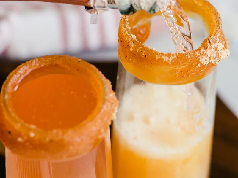 Pouring apple cider mixture into caramel-rimmed champagne flute