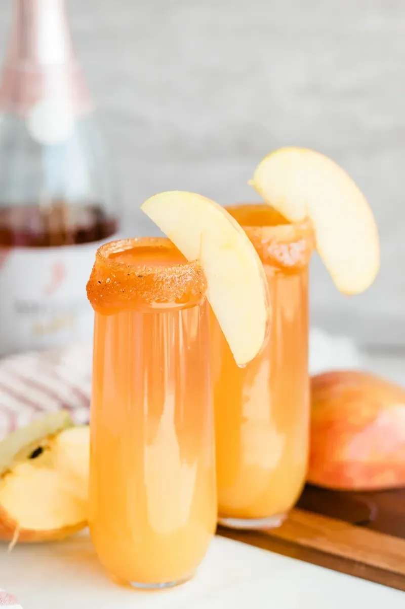 Apple cider mimosa with caramel rim and apple slice garnish showcasing fall flavors