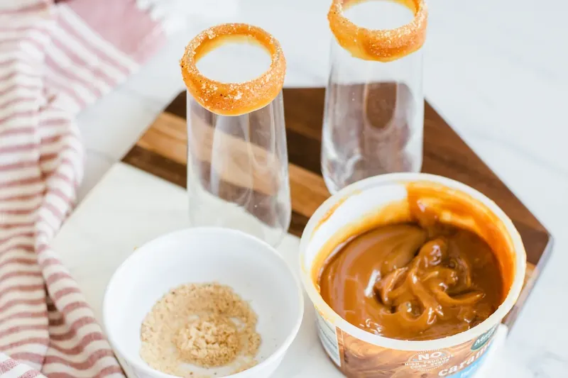 Champagne flutes with caramel dipping sauce and nutmeg for rimming glasses