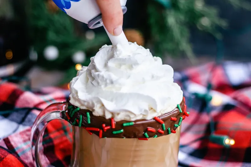Adding whipped cream to boozy Christmas coffee with chocolate rim