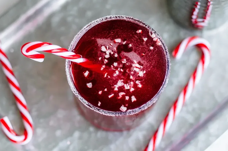 Seltzer water being poured into candy cane margarita to add carbonation
