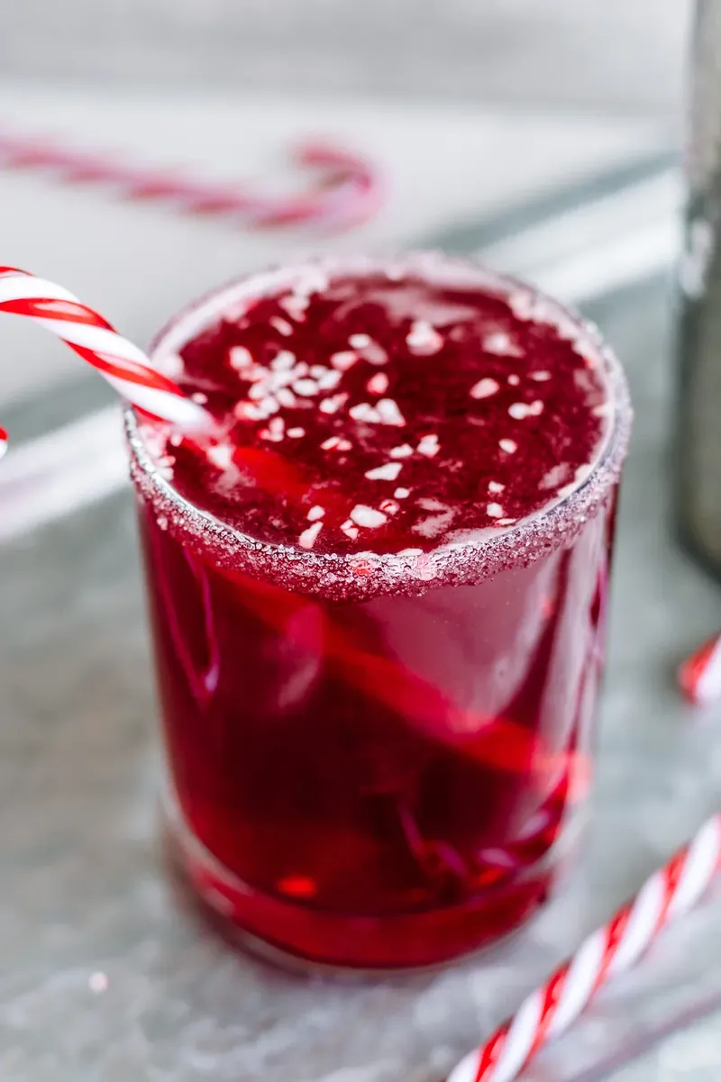 Candy cane margarita with sugar rim, crushed candy canes, and candy cane straw garnish