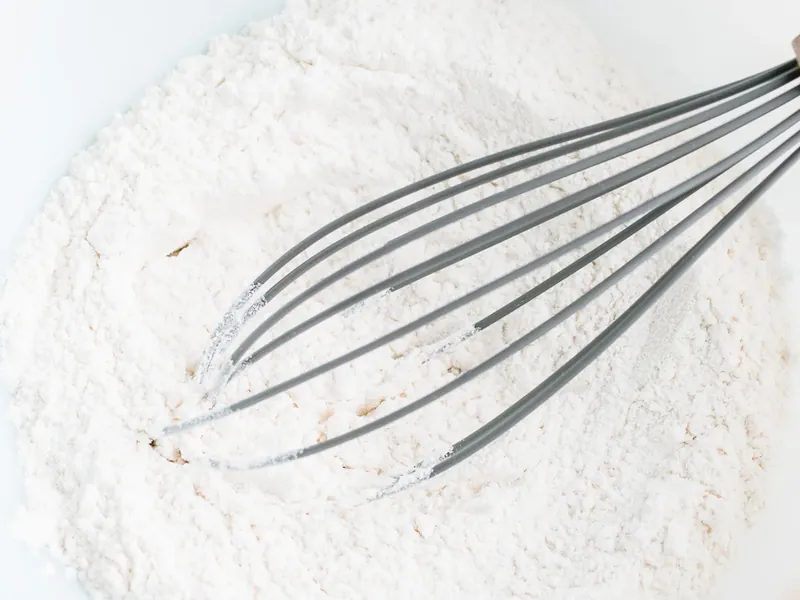 Wire whisk in bowl with flour baking powder baking soda salt and sugar mixed together