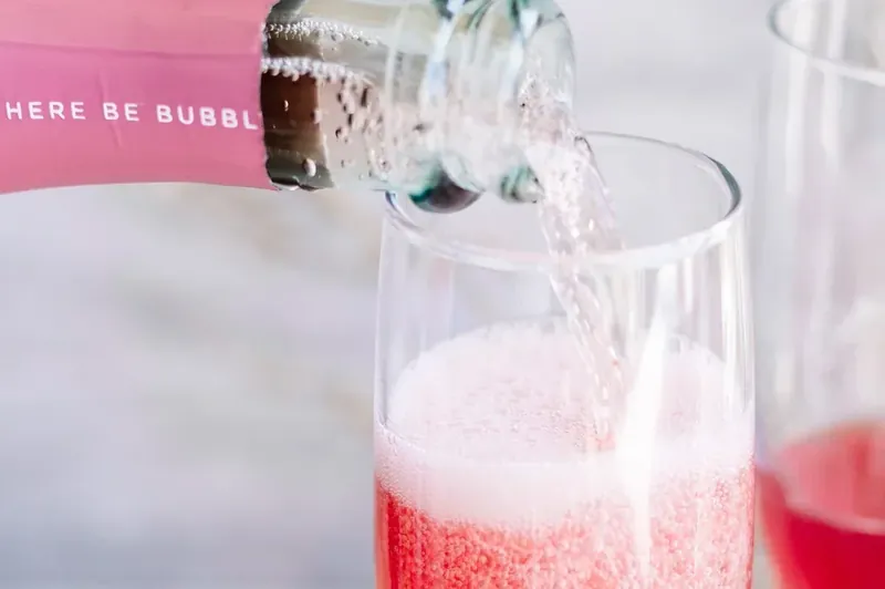 Pouring sparkling wine into champagne flute for Christmas mimosa