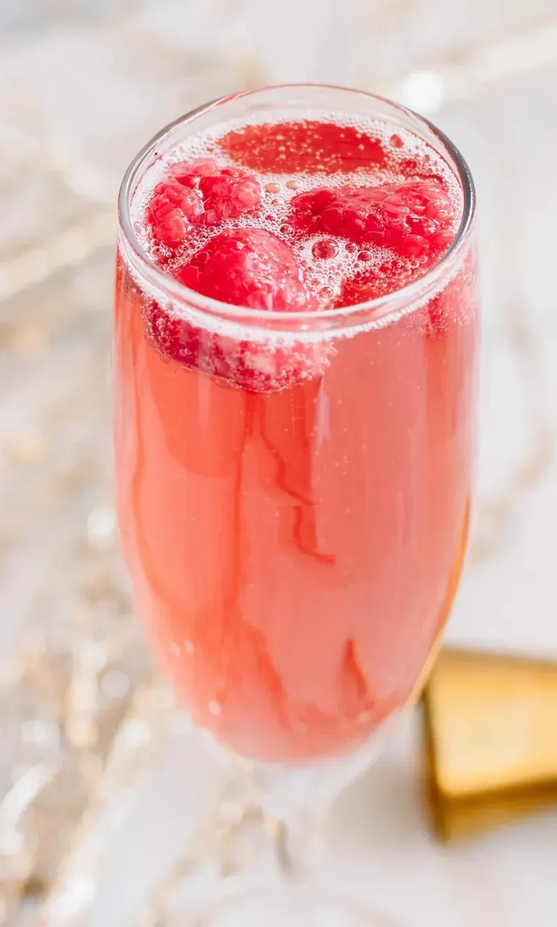 Christmas mimosa cocktail with raspberries and bubbles in champagne flute