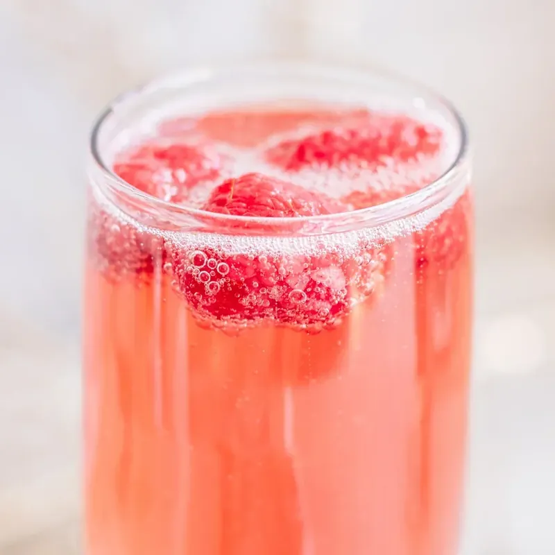 Close up of Christmas mimosa showing bubbles and fresh raspberry detail