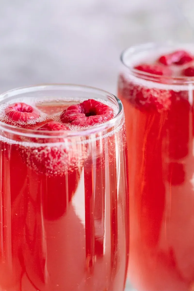 Christmas mimosa with raspberries in foreground with second glass behind