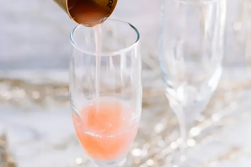 Pouring grapefruit juice into champagne flute for Christmas mimosa