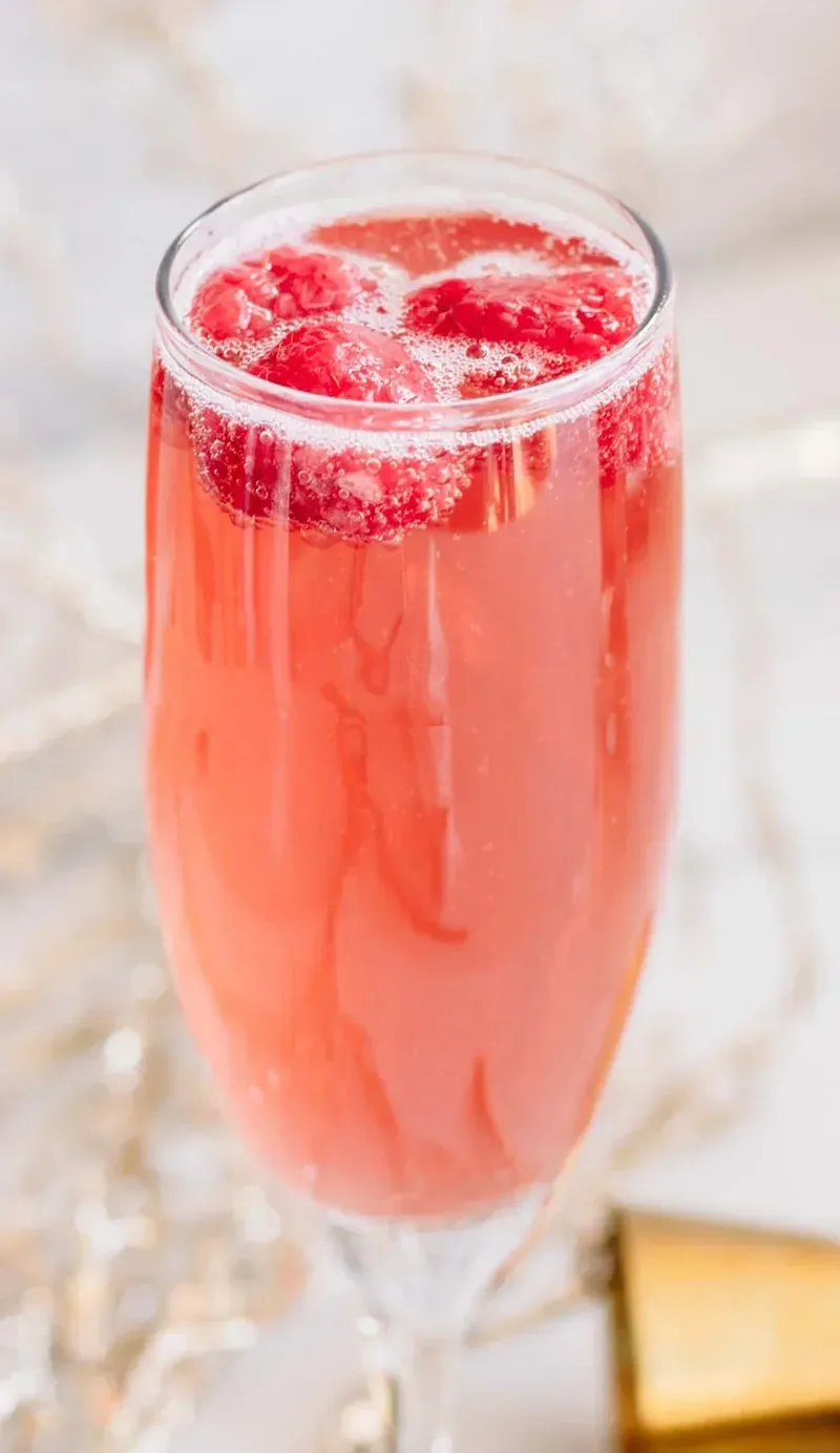 Close up of Christmas mimosa with fresh raspberries floating on top