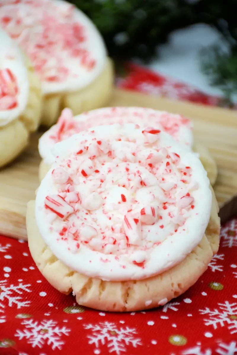 Crumbl candy cane cookies with white peppermint frosting and crushed candy cane pieces on festive red napkin