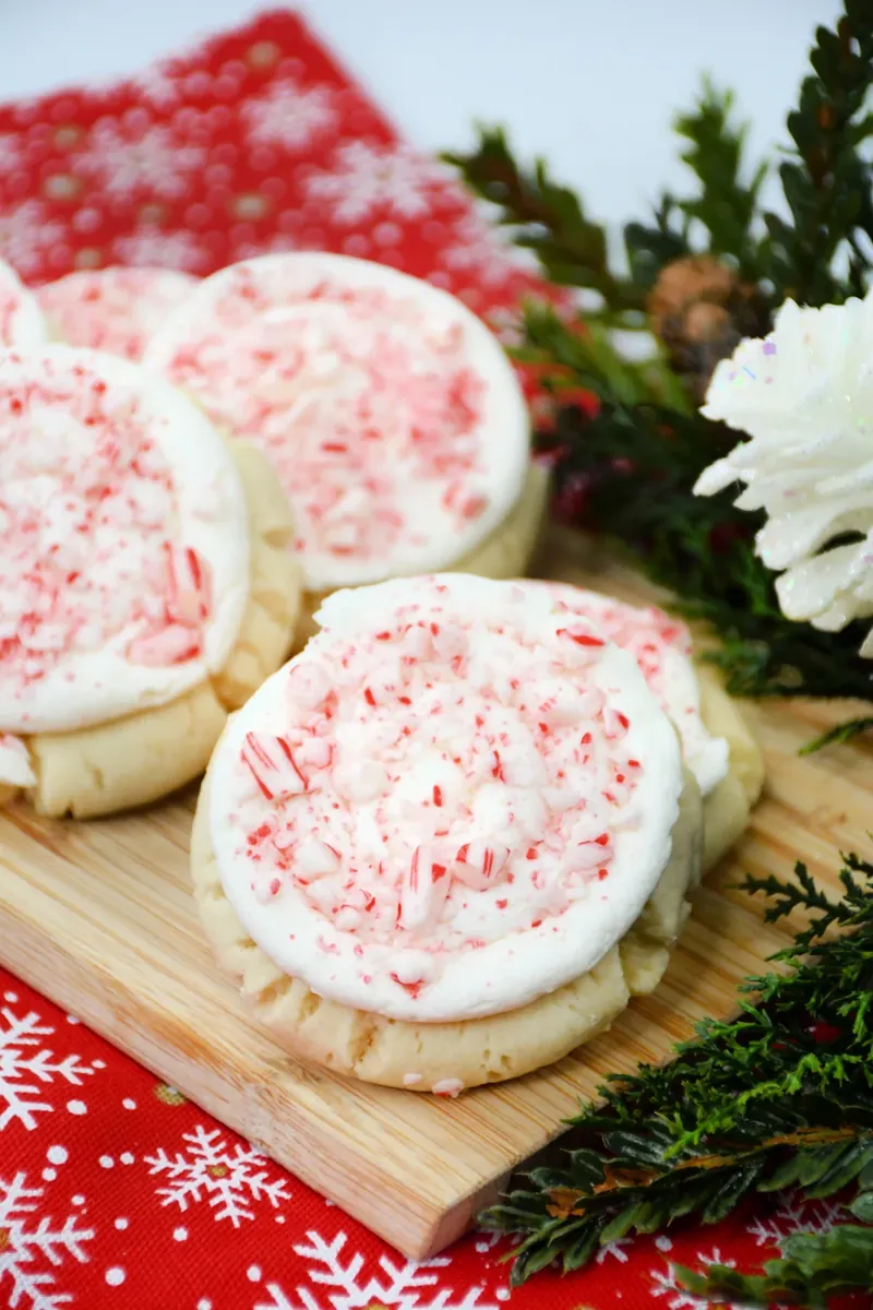 Crumbl candy cane cookies arranged on wooden cutting board with Christmas decorations and red snowflake napkin