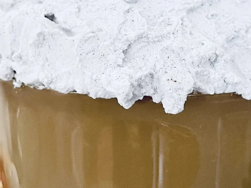 White spackle mixture being applied over styrofoam ball on mug to create whipped cream appearance