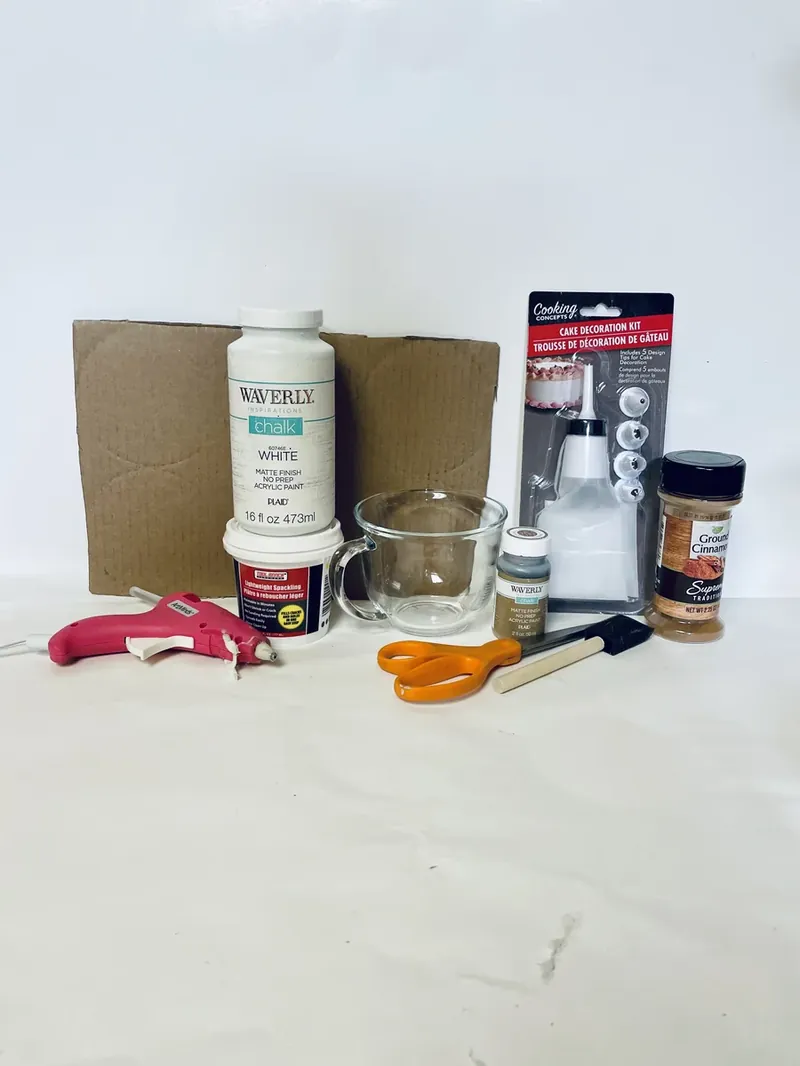 Dollar Tree craft supplies including glass mug, chalk paint, spackle, cake decorating kit, cardboard, scissors, and hot glue gun