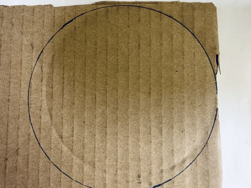 Glass mug flipped upside down with traced circle outline on brown cardboard
