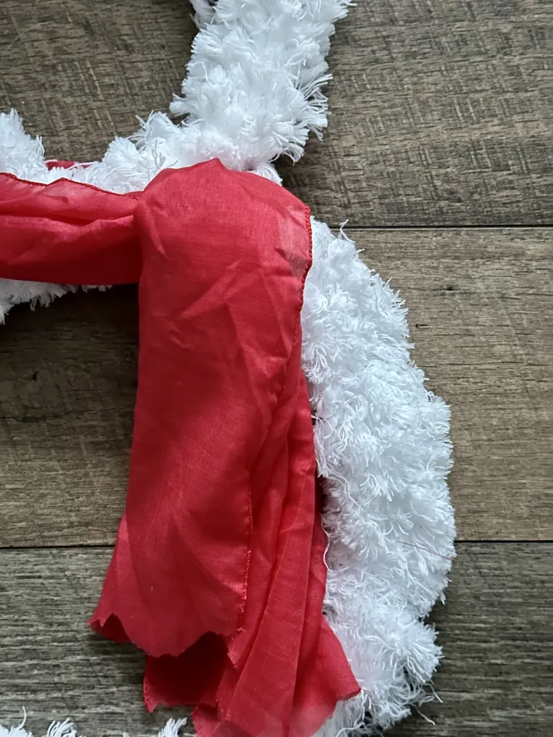 Close up view of completed Dollar Tree fluffy snowman wreath with black hat and red scarf