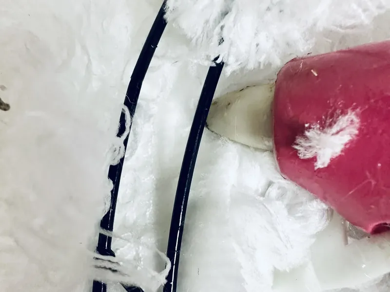 Wrapping white microfiber strips around wire snowman form with hot glue gun