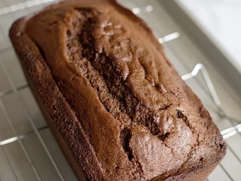 Baked gingerbread loaf cooling on wire cooling rack with golden brown color