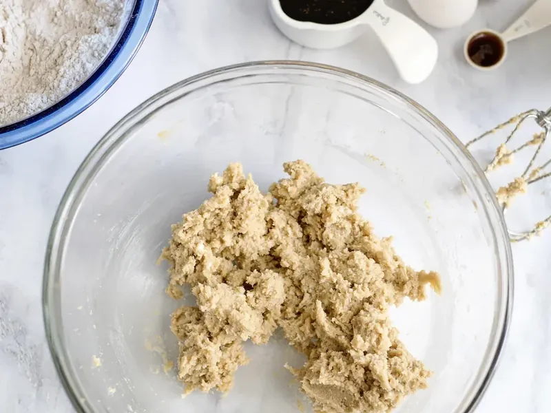 Glass mixing bowl with creamed butter and brown sugar mixture using hand mixer
