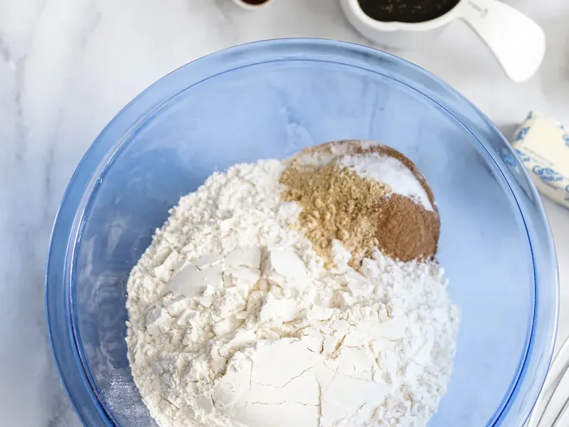 Blue mixing bowl with flour, ginger, cinnamon, nutmeg, baking soda and salt mixed together