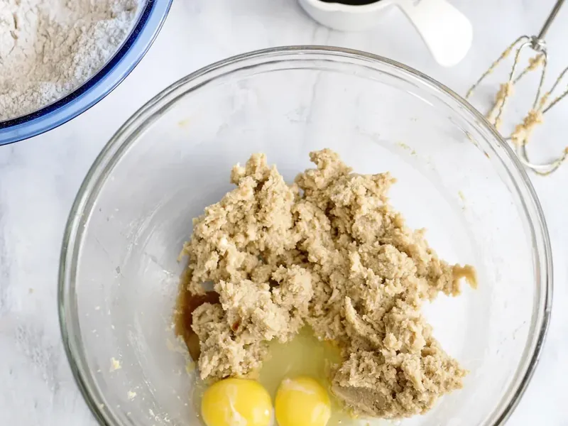 Mixing bowl showing butter mixture with raw eggs and vanilla being incorporated