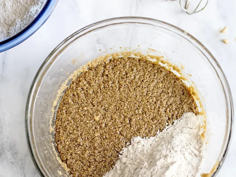 Glass bowl showing wet and dry ingredients being combined with flour mixture partially mixed in