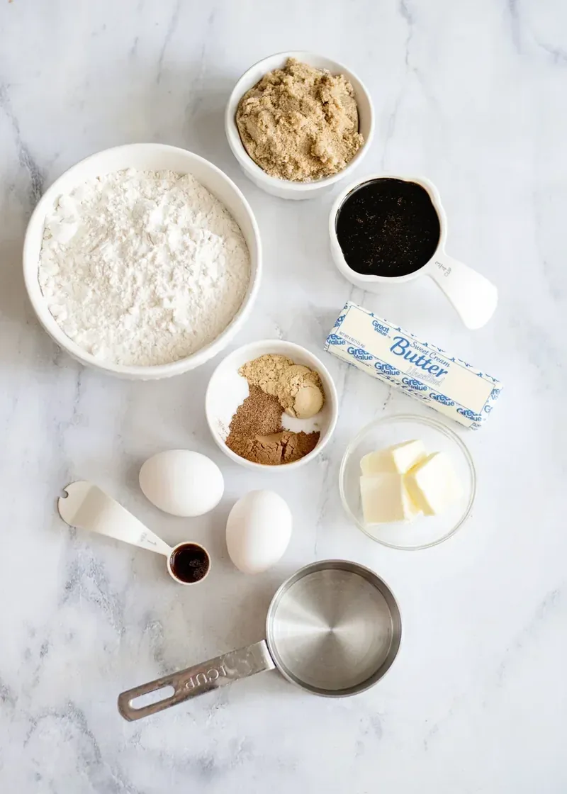 Gingerbread loaf ingredients laid out including flour, spices, molasses, butter, eggs, and brown sugar