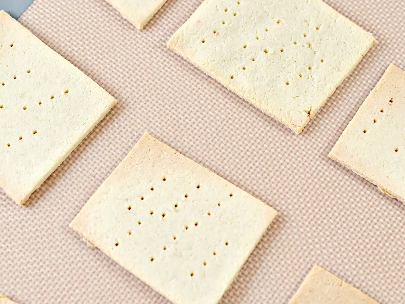 Golden baked keto saltine crackers arranged on parchment paper