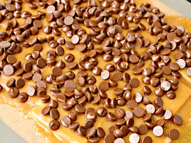 Sugar-free chocolate chips scattered over hot toffee-covered crackers