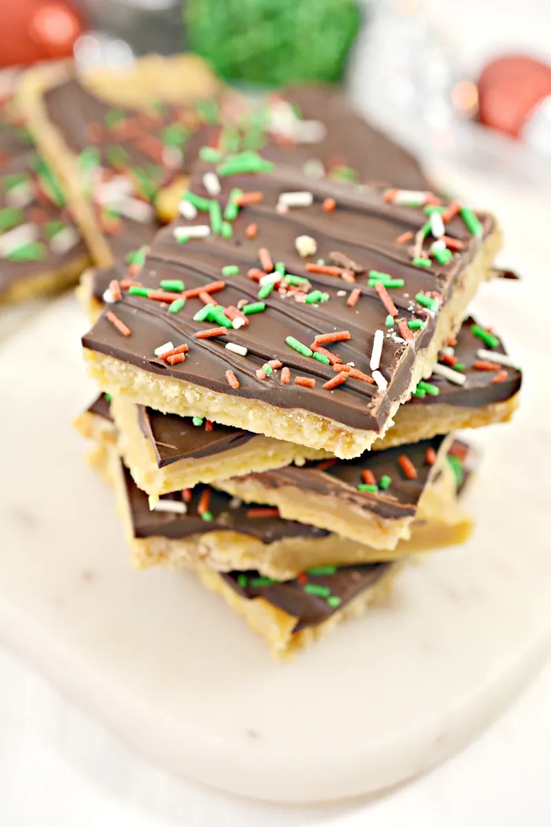 Keto Christmas crack bars stacked with chocolate coating and Christmas sprinkles