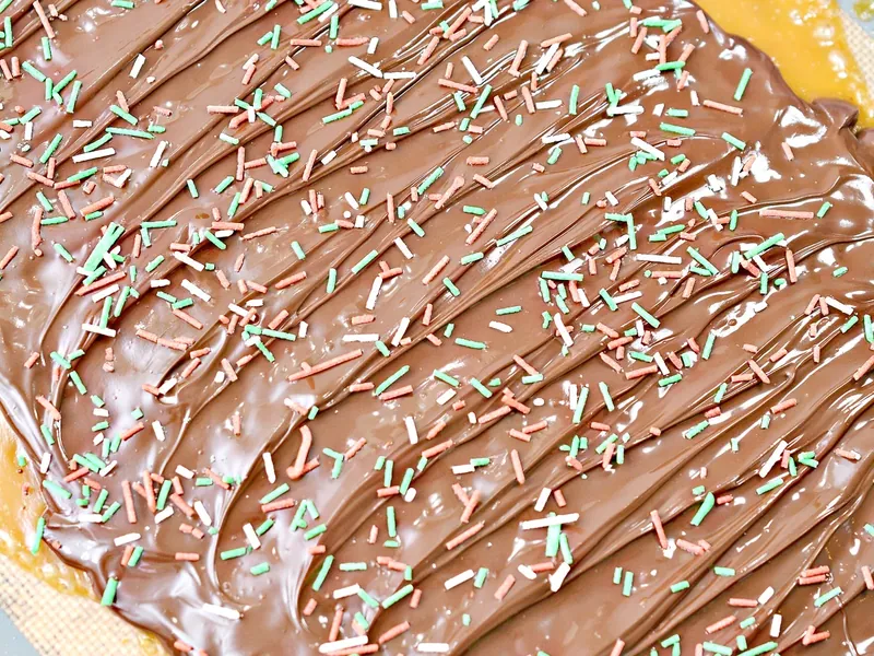 Christmas sprinkles scattered over melted chocolate on keto Christmas crack
