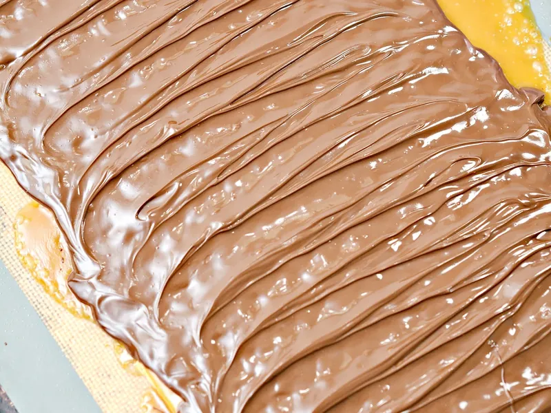 Melted chocolate spread evenly over toffee-covered keto crackers