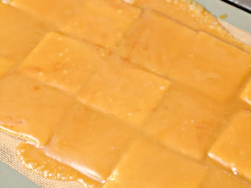 Keto saltines covered with golden toffee mixture on baking sheet