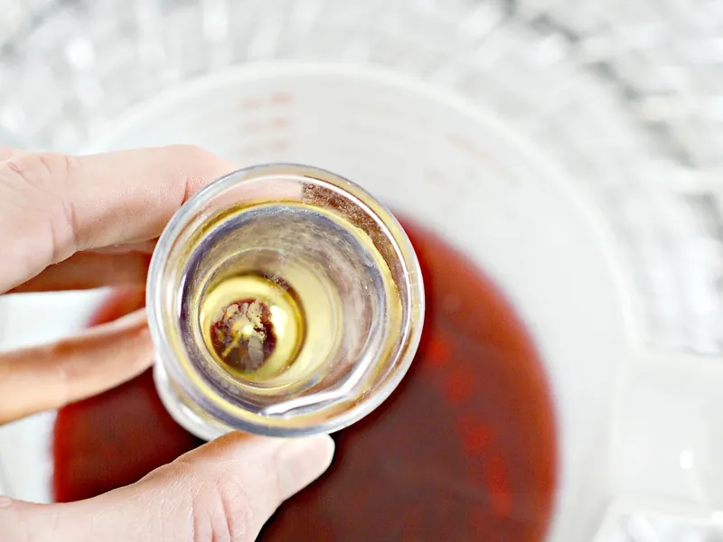 Shot of tequila being added to cranberry tea mixture