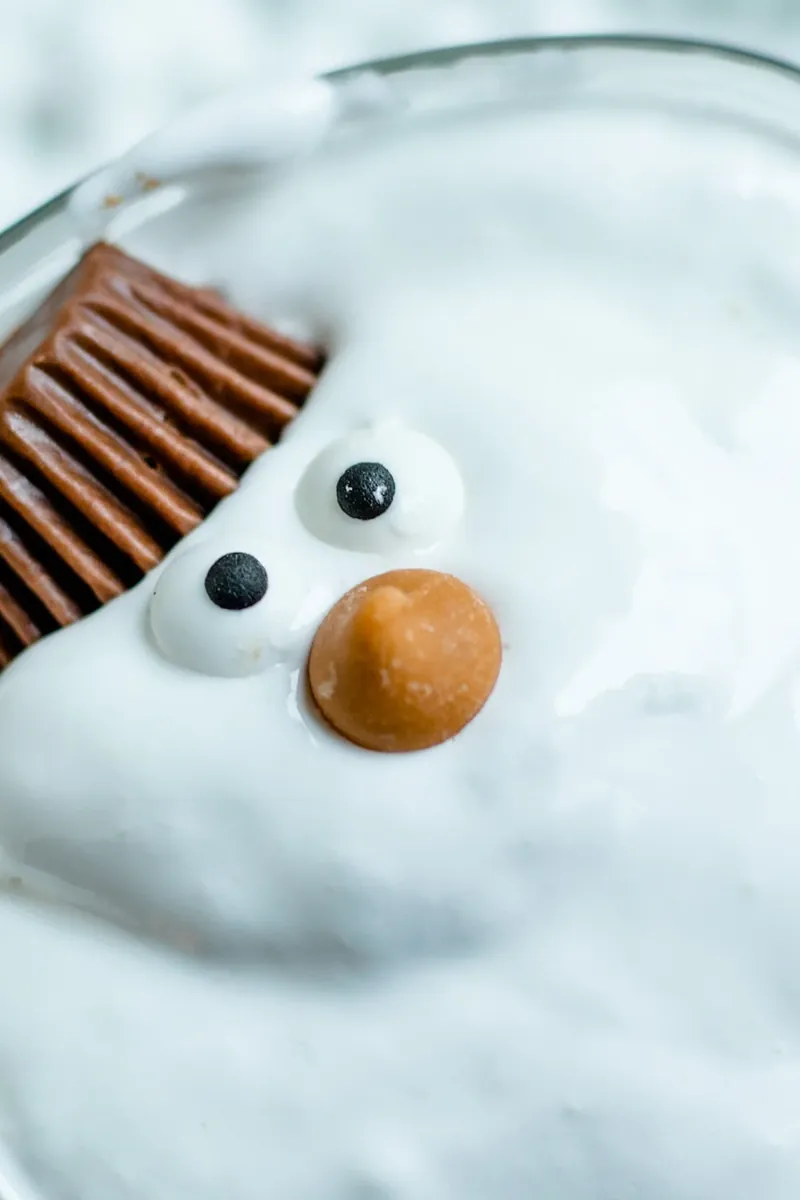 Close-up view of melted snowman margarita showing detailed candy eyes, butterscotch nose, and Reese's hat