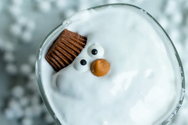 Melted snowman margarita being decorated with candy eyes, butterscotch nose, and chocolate hat