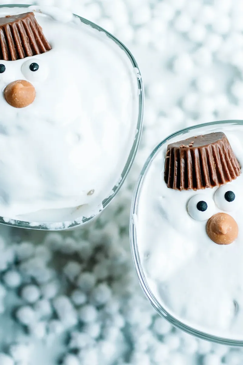 Two completed melted snowman margaritas side by side with marshmallow snowman decorations