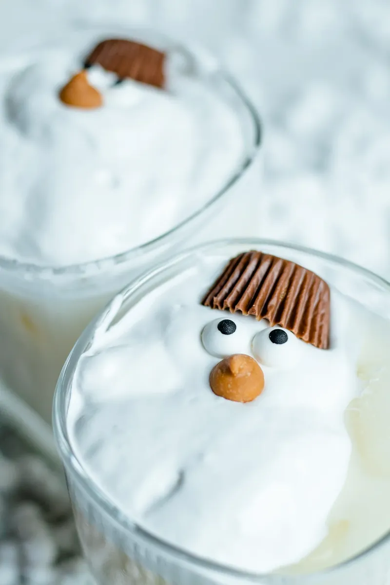 Completed melted snowman margaritas with marshmallow fluff snowman faces and chocolate hat garnishes