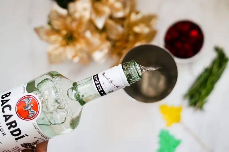 Pouring Bacardi rum into cocktail shaker with ice for Reindeer Bacardi Punch