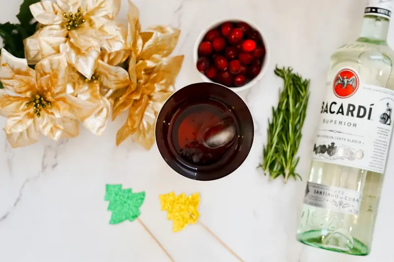 Pouring Bacardi cranberry mixture into glass with ice and topping with ginger ale