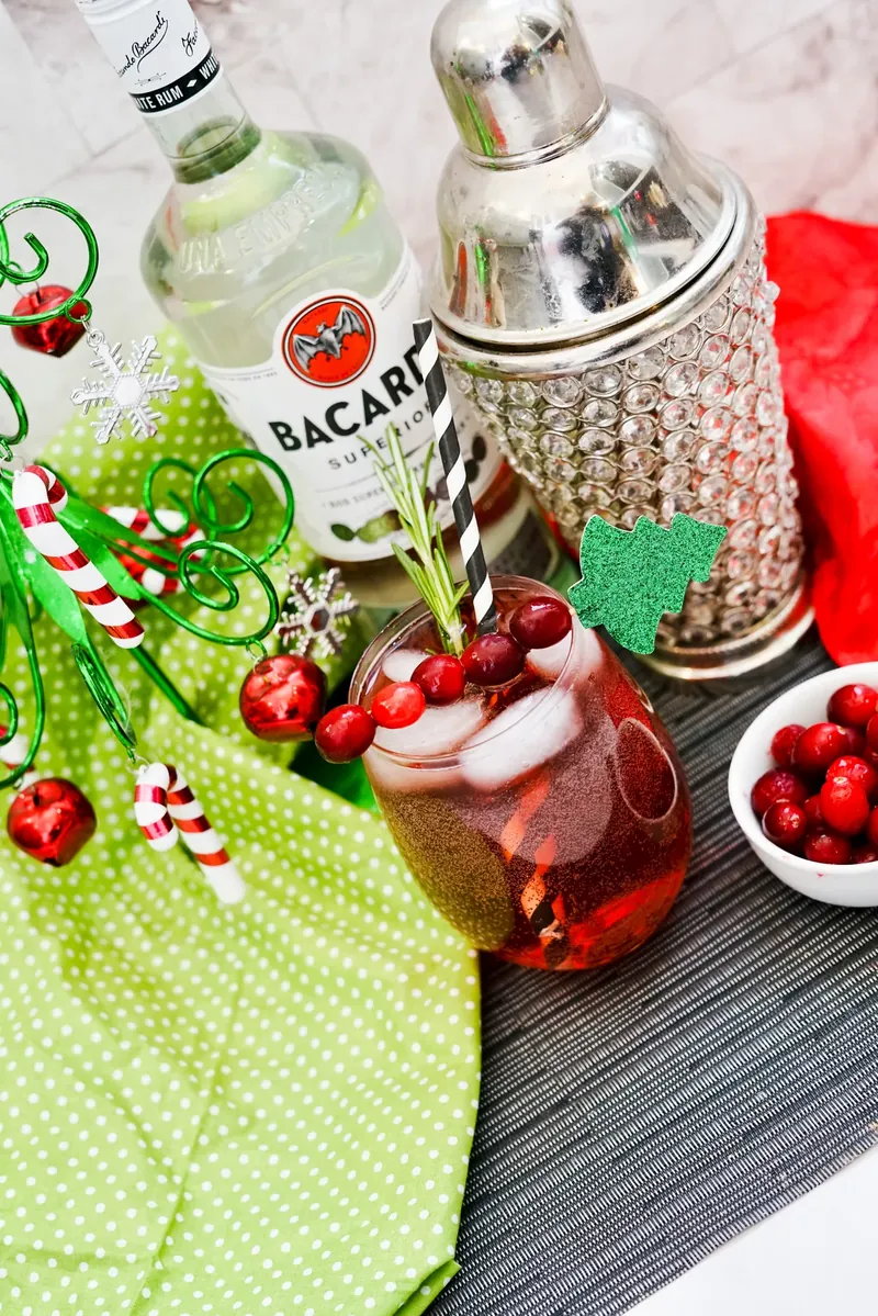 Reindeer Bacardi Punch cocktail with cranberry garnish and rosemary sprig in glass