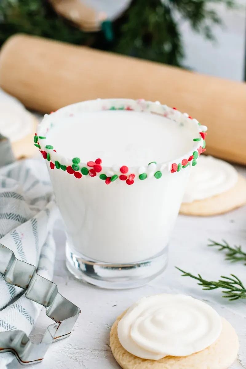 Creamy white sugar cookie margarita with colorful Christmas sprinkle rim and sugar cookies