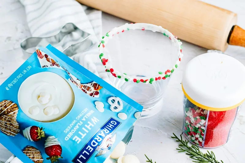 White melting chocolate being prepared with Christmas sprinkles and cocktail glass
