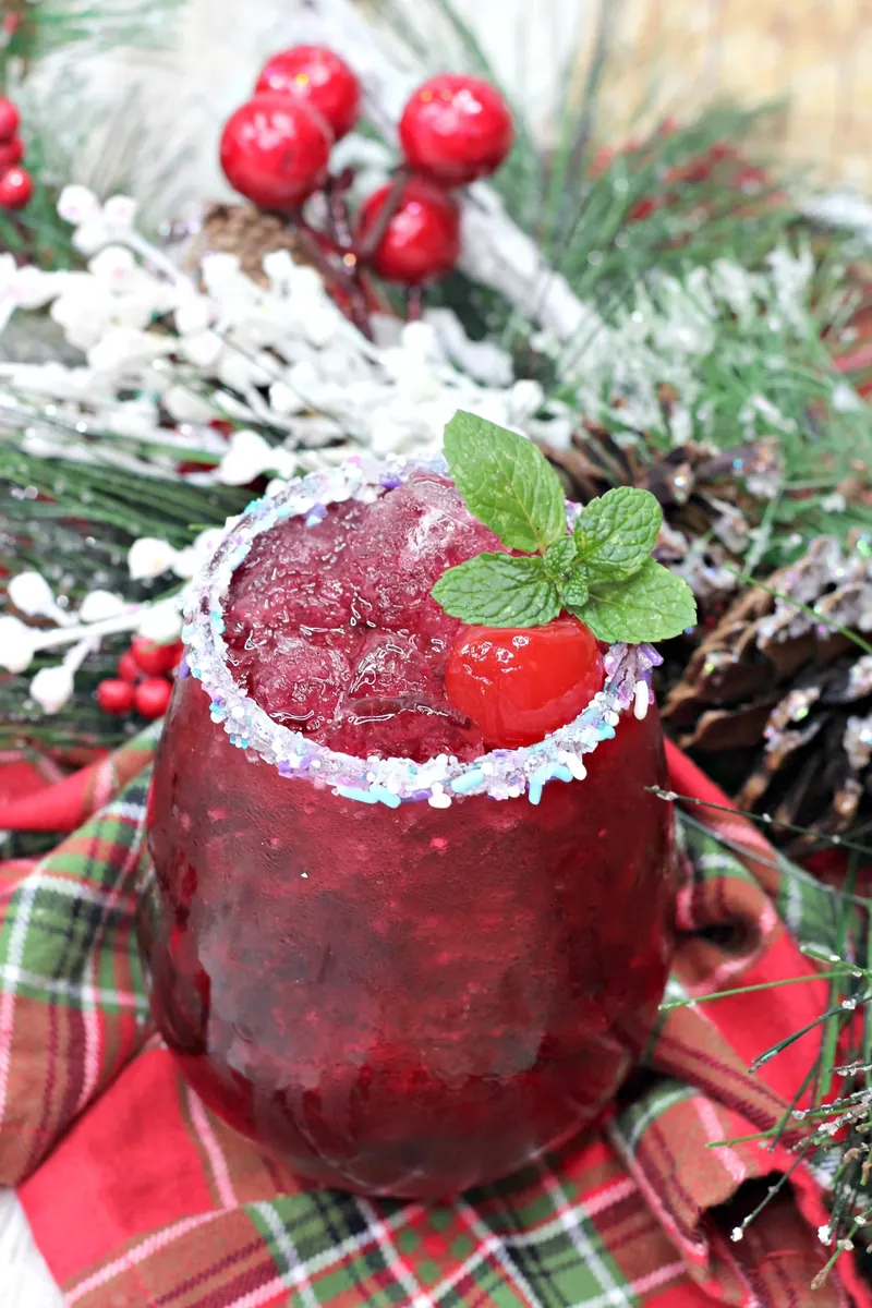 Sugar plum cocktail garnished with fresh mint and cherry in festive holiday setting