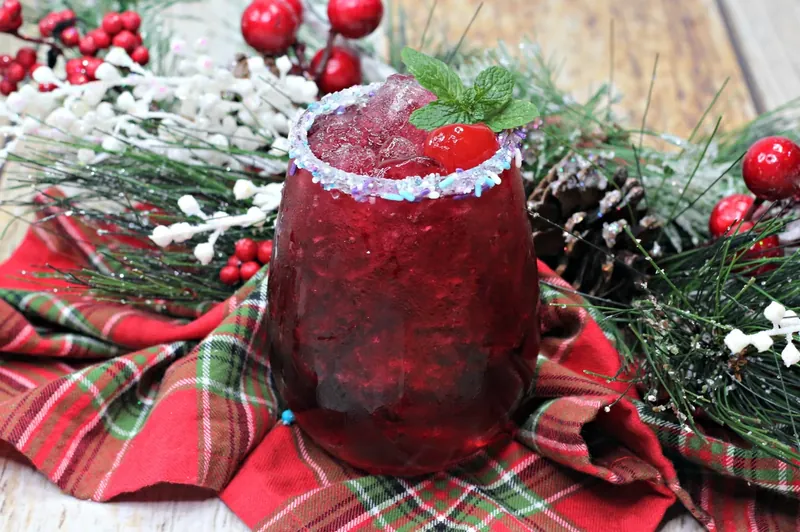 Glass being prepared with sugar plum sprinkles on rim for cocktail