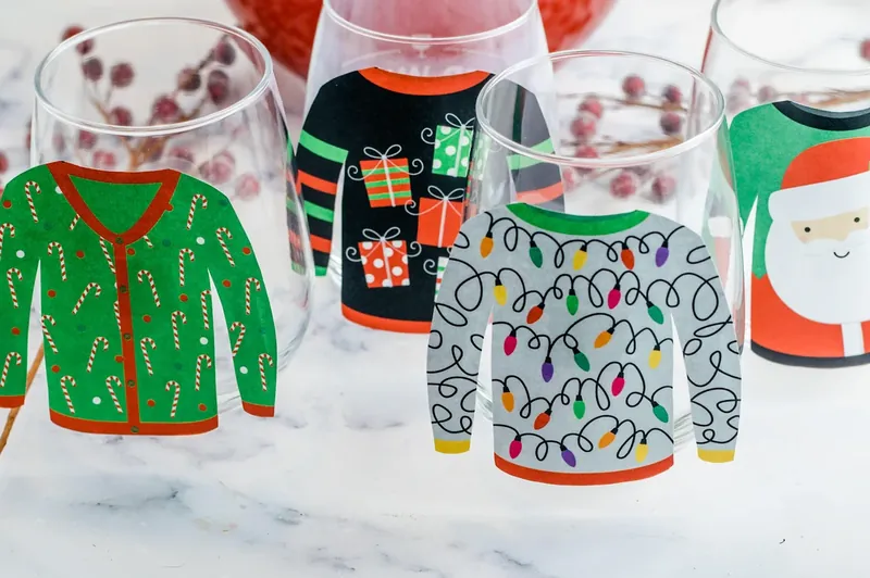 Empty glasses decorated with printed ugly Christmas sweater designs