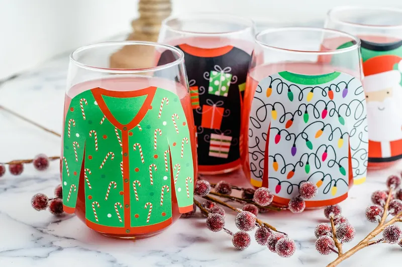 Pouring pink margarita punch into glasses decorated with Christmas sweater designs