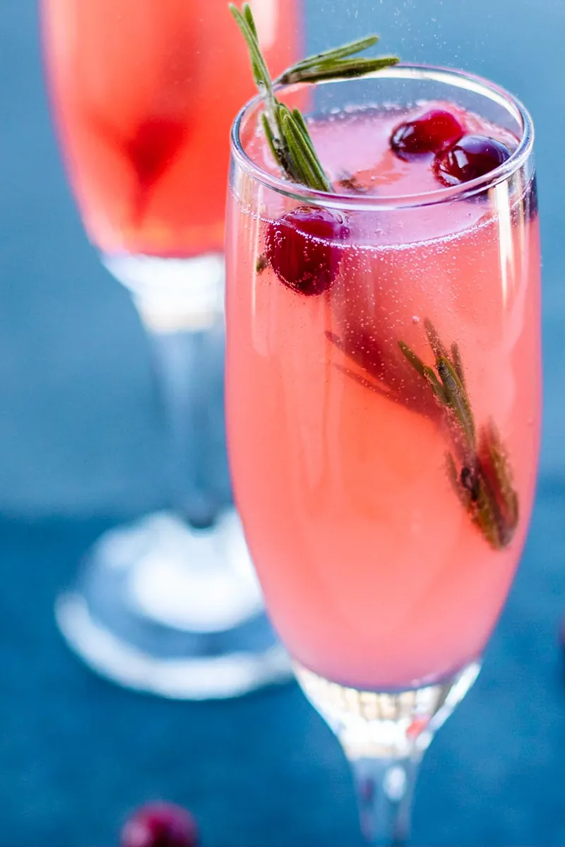 Elegant vanilla cranberry mimosa with rosemary garnish and champagne bubbles