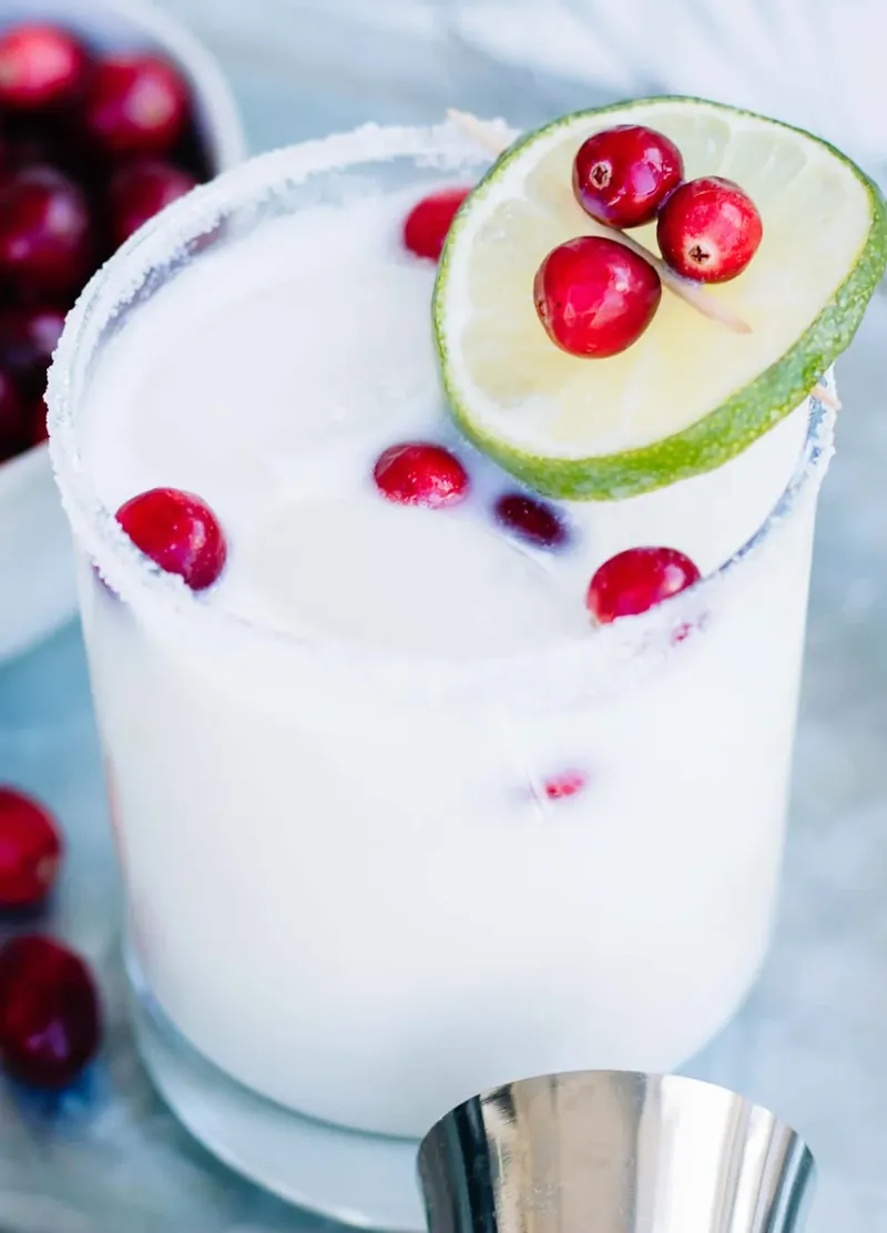 White Christmas Margarita with peppermint rim, lime wheel and fresh cranberries in tall glass