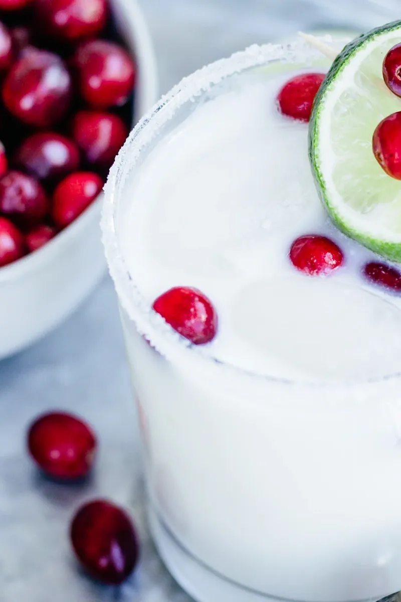 Close up of White Christmas Margarita showing peppermint rim and cranberry garnish